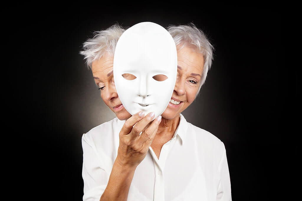 older woman hiding happy and sad face behind mask older woman hiding happy and sad face behind mask