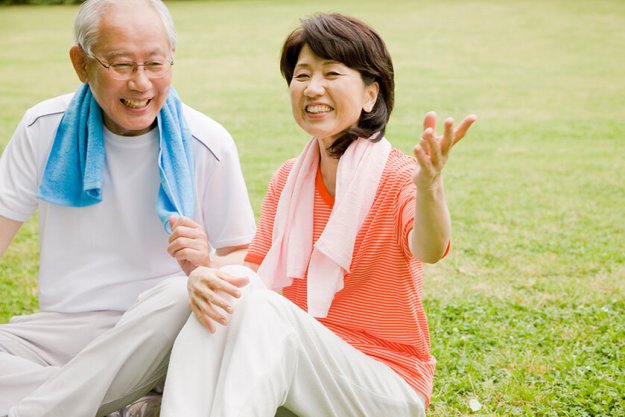 An elderly couple in athletic clothes sitting on the lawn in the park An elderly couple in athletic clothes sitting on the lawn in the park