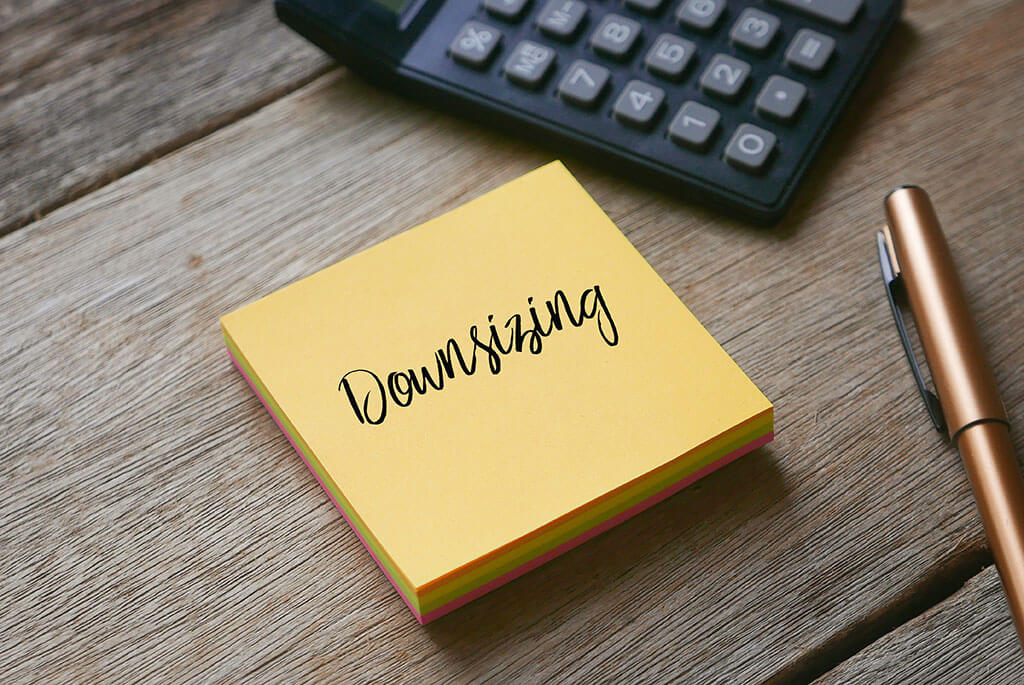 Calculator,pen and yellow sticky notes written with Downsizing