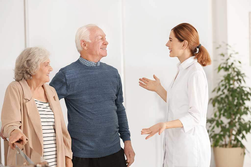 Elderly spouses with female caregiver in room Elderly spouses with female caregiver in room