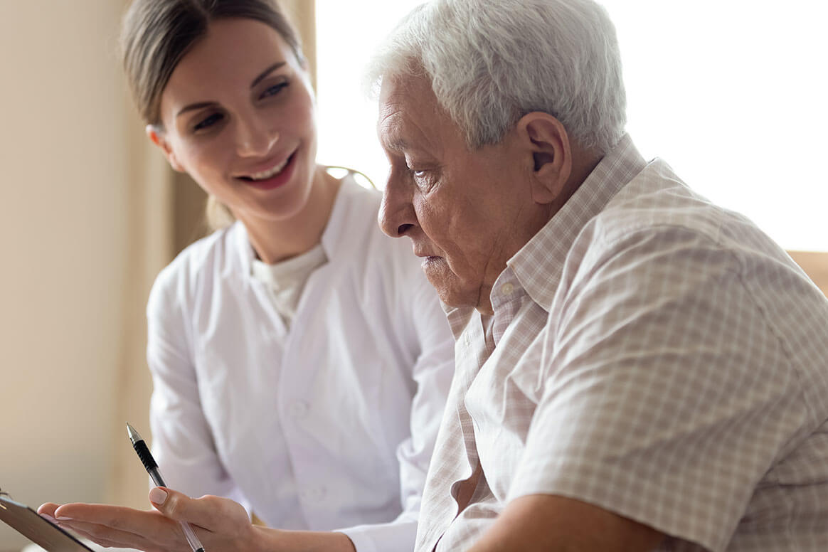 Older man patient and young nurse talking indoors Older man patient and young nurse talking indoors