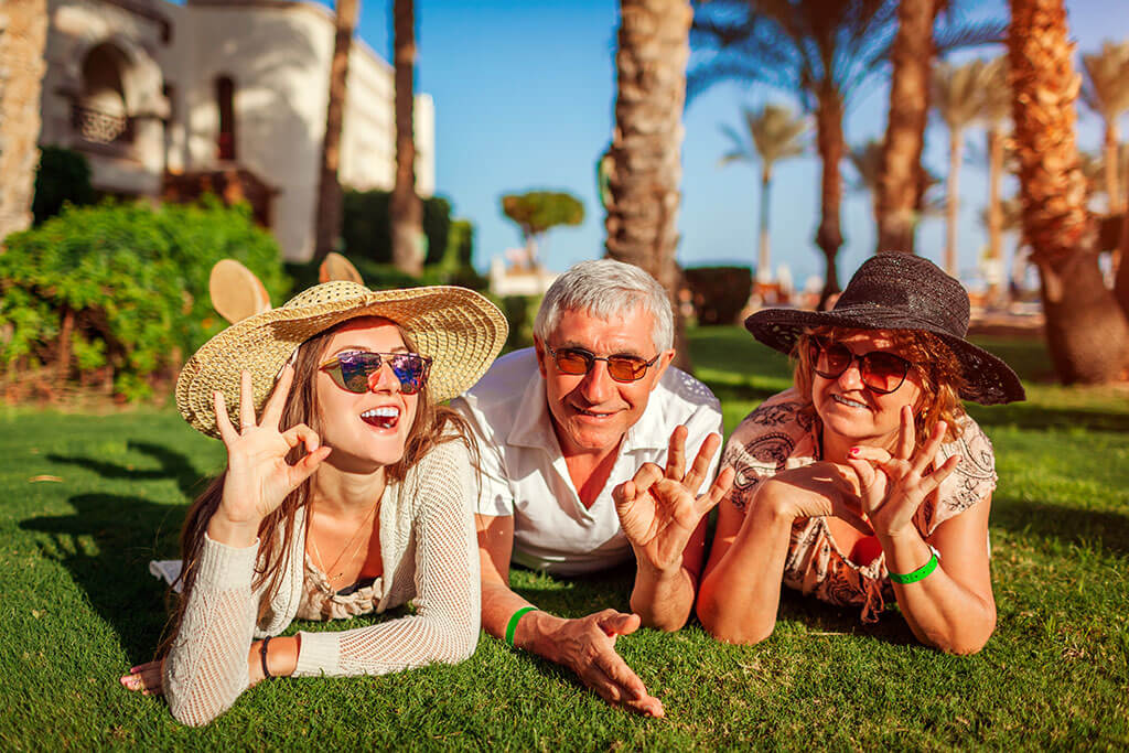 Senior couple lying on grass with adult daughter by hotel Senior couple lying on grass with adult daughter by hotel