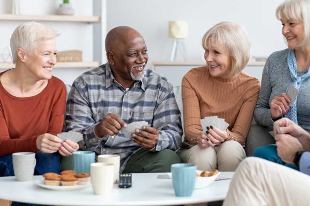 Senior friends playing cards while drinking tea at home