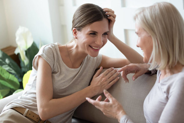 Smiling adult daughter listening to older mother Smiling adult daughter listening to older mother