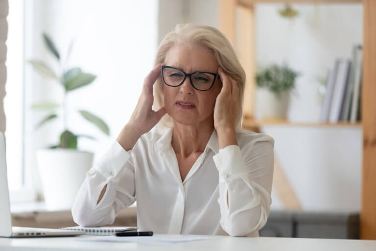 Unhappy 60 years old businesswoman massaging temples close up