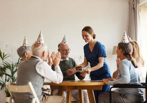 Young nurse bringing birthday cake with candle for senior man