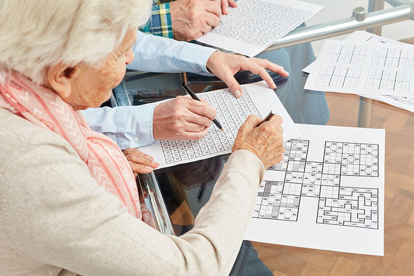 Alte Frau löst Sudoku Rätsel als Gedächtnistraining