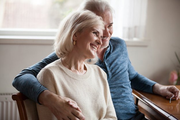 Happy thoughtful spouses talking sitting at home