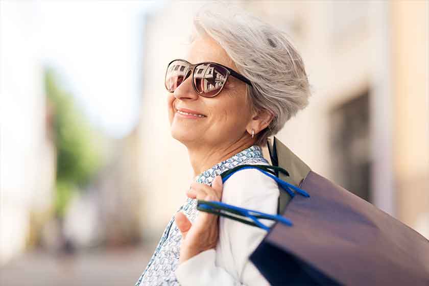 senior woman in sunglasses with shopping bags in city