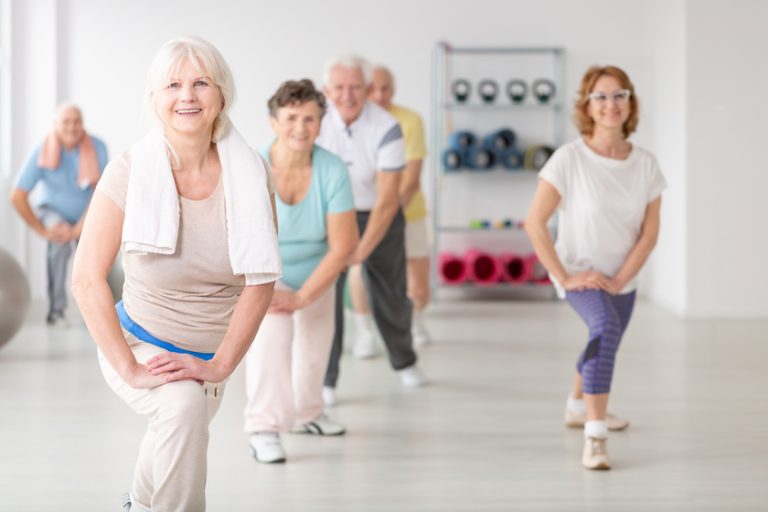 Smiling senior woman with towel exercising during fitness classe