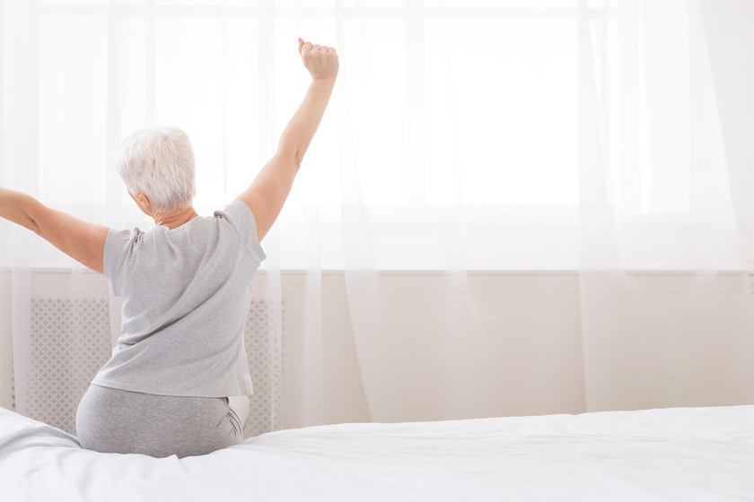 Well slept senior woman stretching with arms raised on bed Well slept senior woman stretching with arms raised on bed