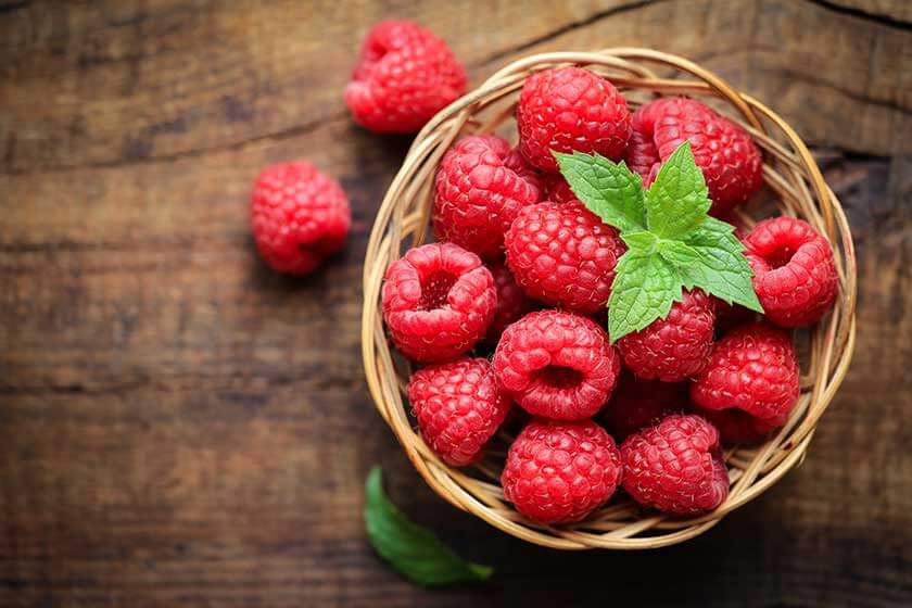 Fresh ripe red raspberries in a wicjer bowl Fresh ripe red raspberries in a wicjer bowl