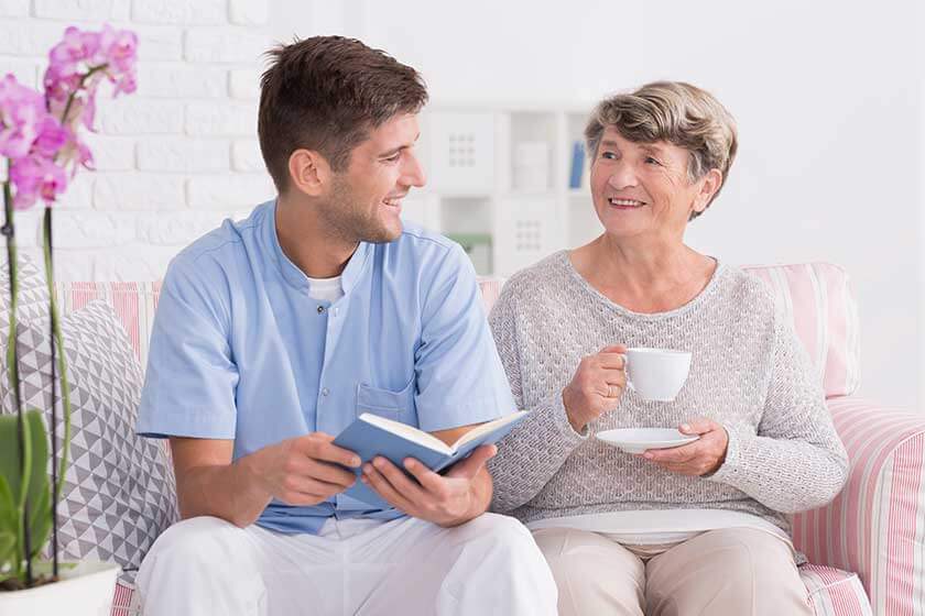 Professional carer reading to senior Professional carer reading to senior
