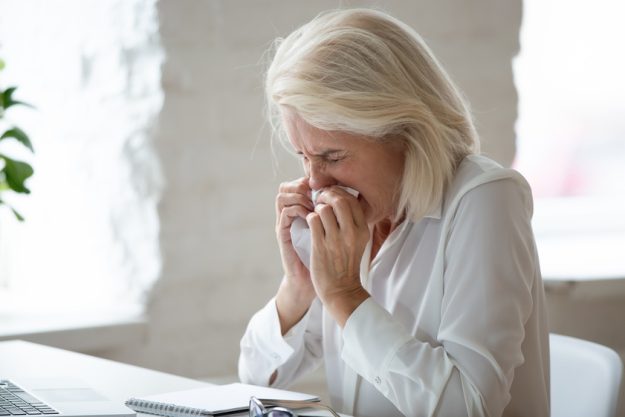 Unhappy 60 years old businesswoman sneeze close up. Unhappy 60 years old businesswoman sneeze close up.