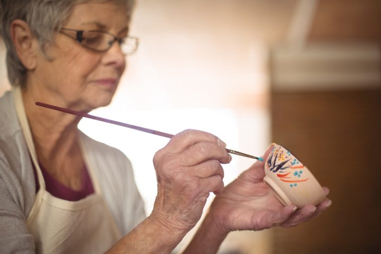 Close-up of female potter painting on bowl