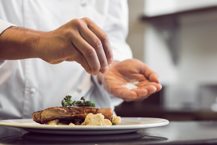 Closeup mid section of a chef putting salt Closeup mid section of a chef putting salt