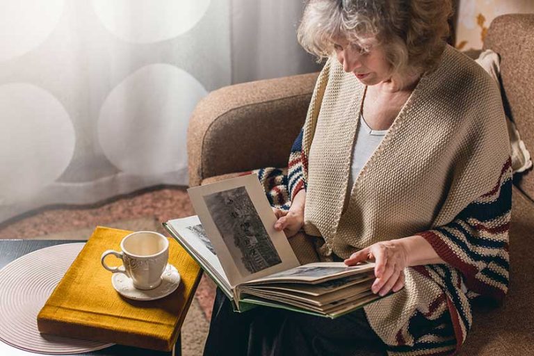 an elderly woman looks at photo albums