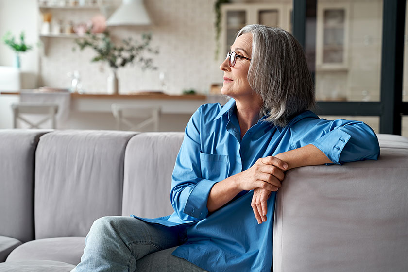 Calm relaxed mature older woman relaxing sitting on couch at home
