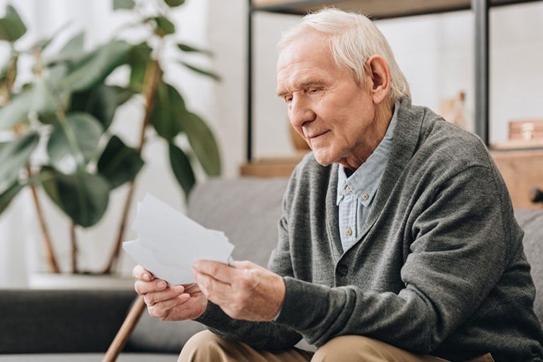 happy pensioner with grey hair looking at photos in living room