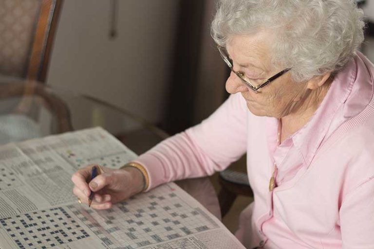 Close-up of an old senior woman, 80s adult, grandmother, making crossword puzzles