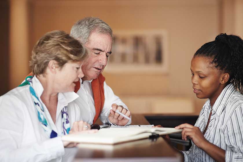 A senior couple filling out forms at the hotel reception desk