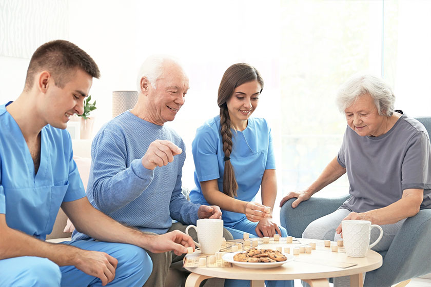 Senior people playing bingo with their caregivers indoors