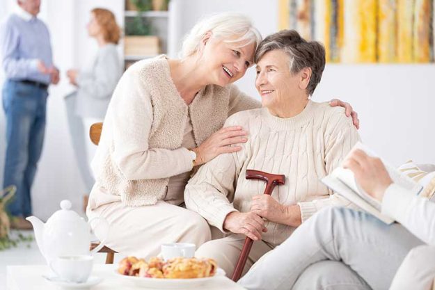 Two smiling senior best friends spending time together at school reunion