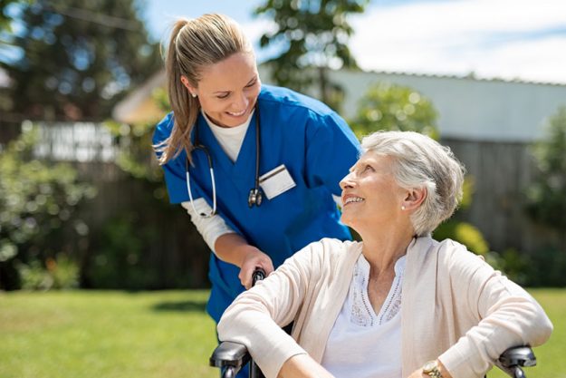 Happy caregiver with elder patient on the wheelchair Happy caregiver with elder patient on the wheelchair