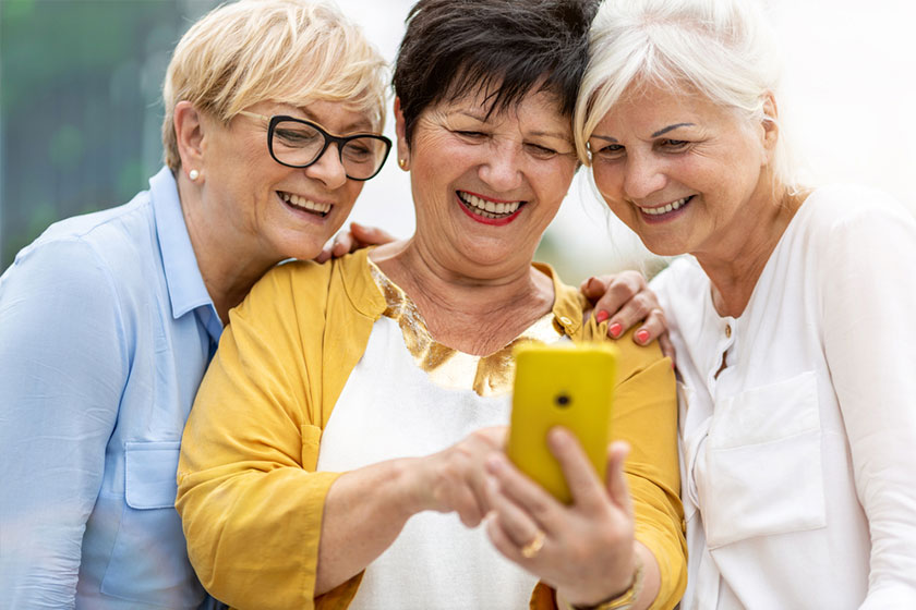 Mature women using smartphone and laughing Mature women using smartphone and laughing