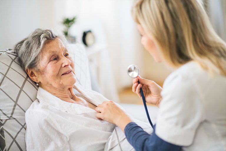 A health visitor examining a sick senior woman lying in bed
