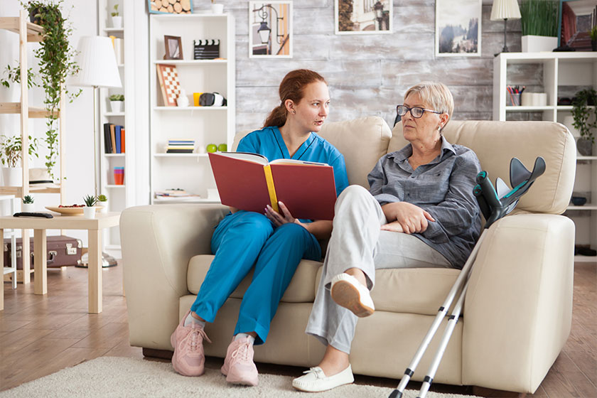 Female nursing reading a book for a senior woman Female nursing reading a book for a senior woman