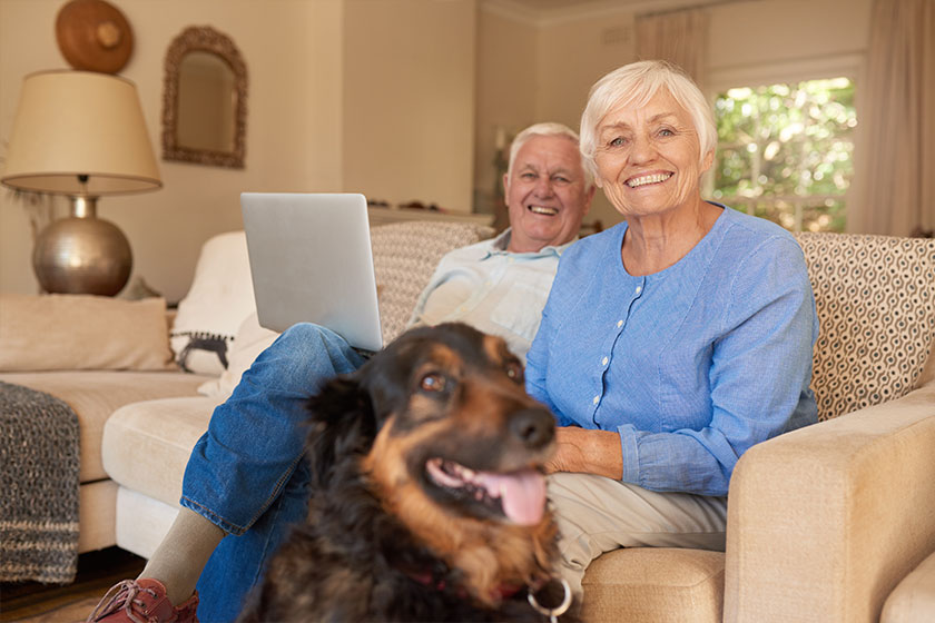 Smiling senior couple relaxing with their dog at home