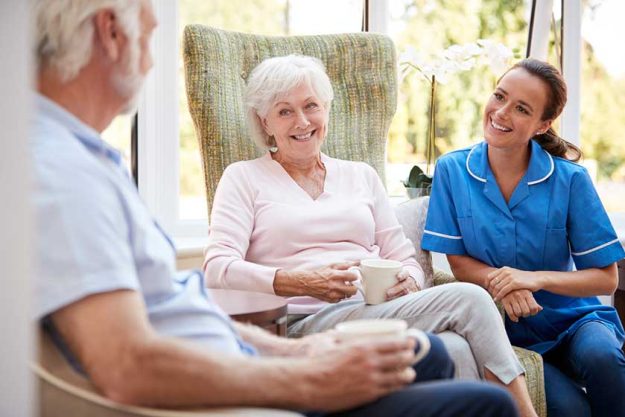 Senior Couple Sitting In Chair And Talking With Nurse Senior Couple Sitting In Chair And Talking With Nurse