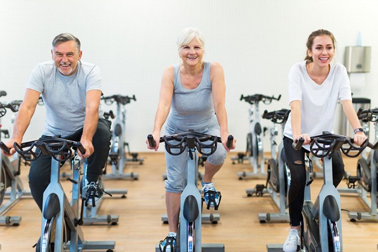 Confident seniors on exercise bikes in spinning class at gym