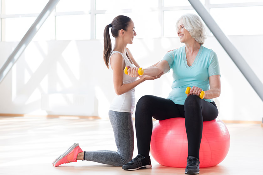 Joyful female coach working out with an elderly woman Joyful female coach working out with an elderly woman