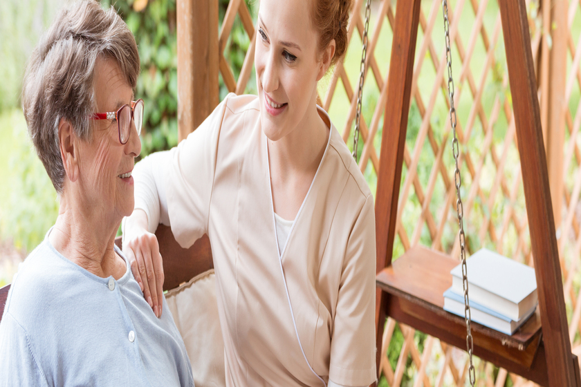 Tender caregiver with a happy elderly woman sitting on a wooden A Guide To Companion Care Service In Terrytown, LA 55 Plus Apartments