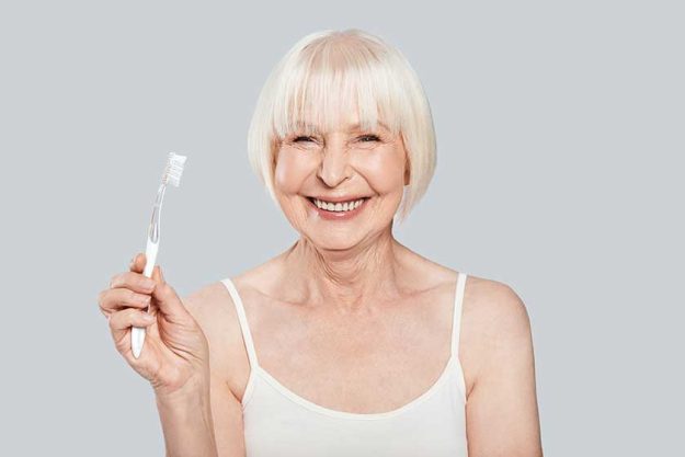Smiling senior woman holding toothbrush and standing Smiling senior woman holding toothbrush and standing