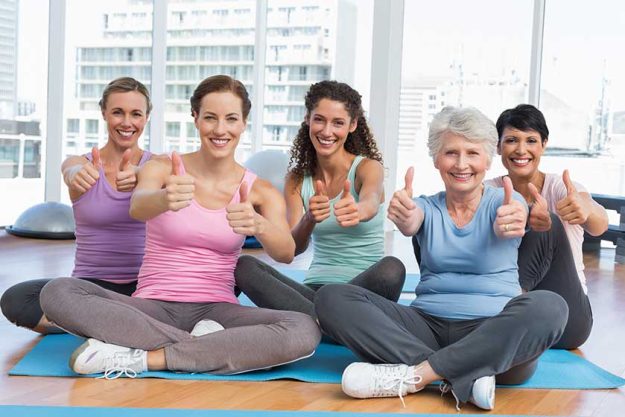 Women gesturing thumbs up in yoga class