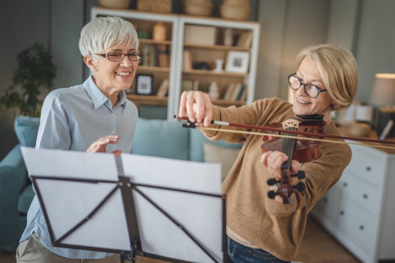 Private music teacher give violin lesson mature senior woman at