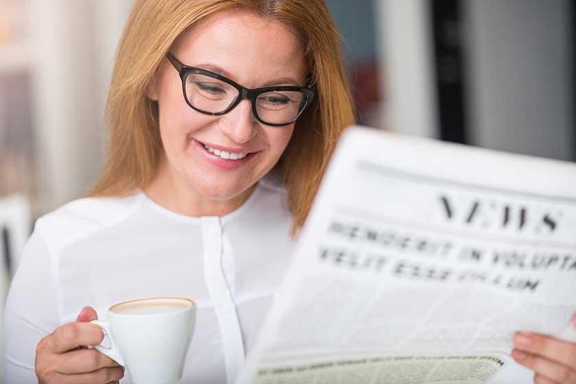 Cheerful woman reading newspaper Cheerful woman reading newspaper