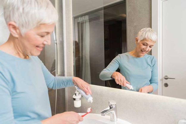 Senior woman putting tooth paste on toothbrush Senior woman putting tooth paste on toothbrush