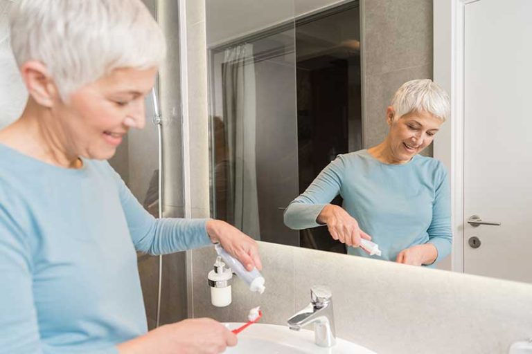 Senior woman putting tooth paste on toothbrush