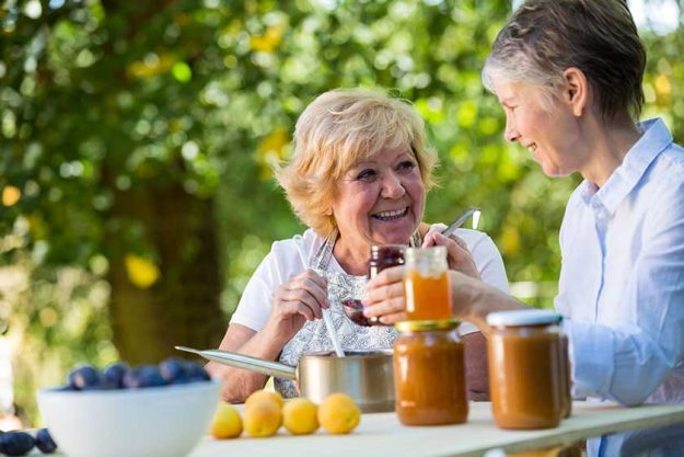 Senior women filling jam in a bottle