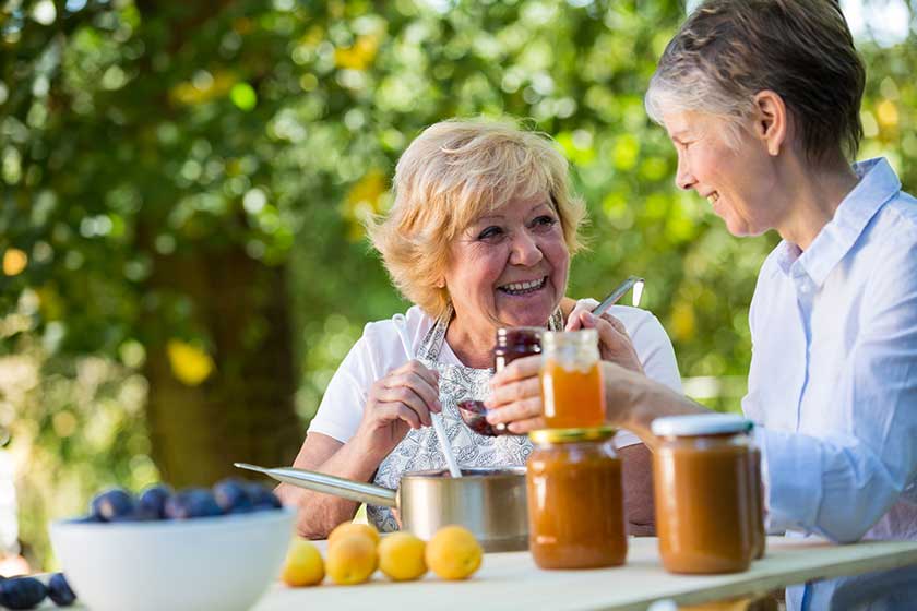 Senior women filling jam in a bottle Senior women filling jam in a bottle