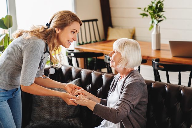 Care of senior woman by caretaker at home