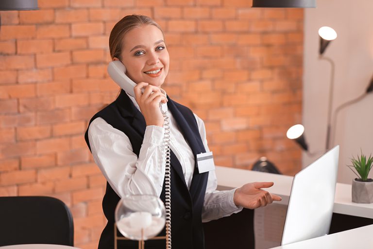 Young female receptionist talking by telephone