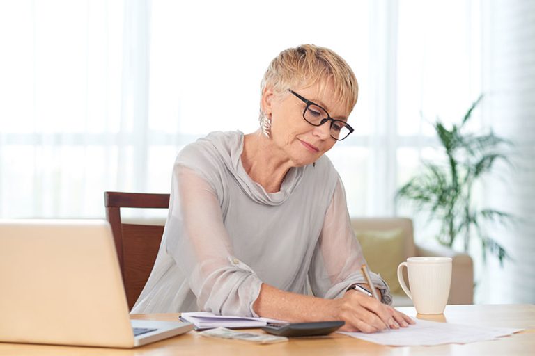 Elegant seniot woman writing household monthly expenses