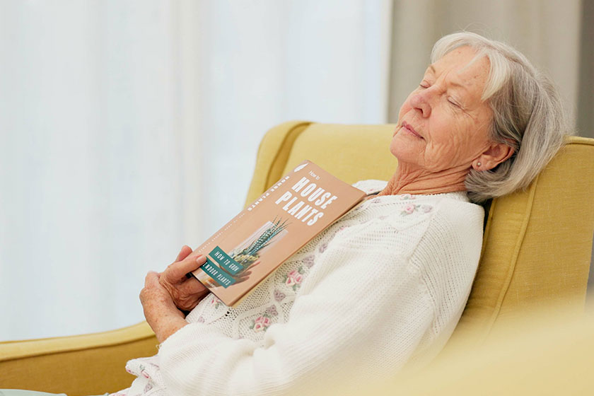 Relax, book and senior woman sleeping in the living room of her modern house on a weekend. Calm, peace and elderly female person in retirement taking a nap after reading a story or novel at home