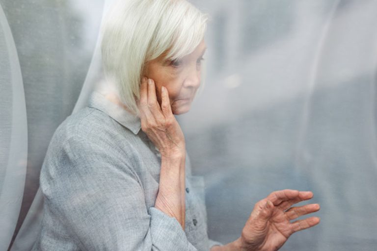 Depressed senior woman touching face