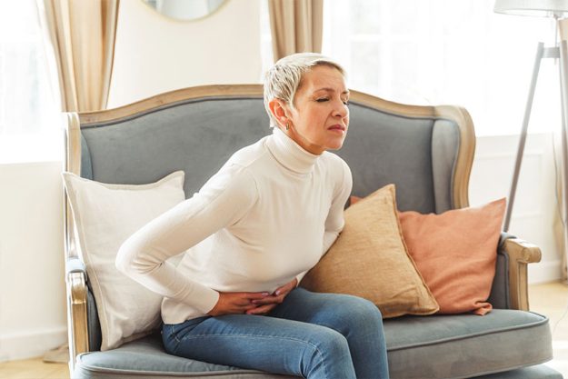 Unhappy elderly woman bending double with a stomachache